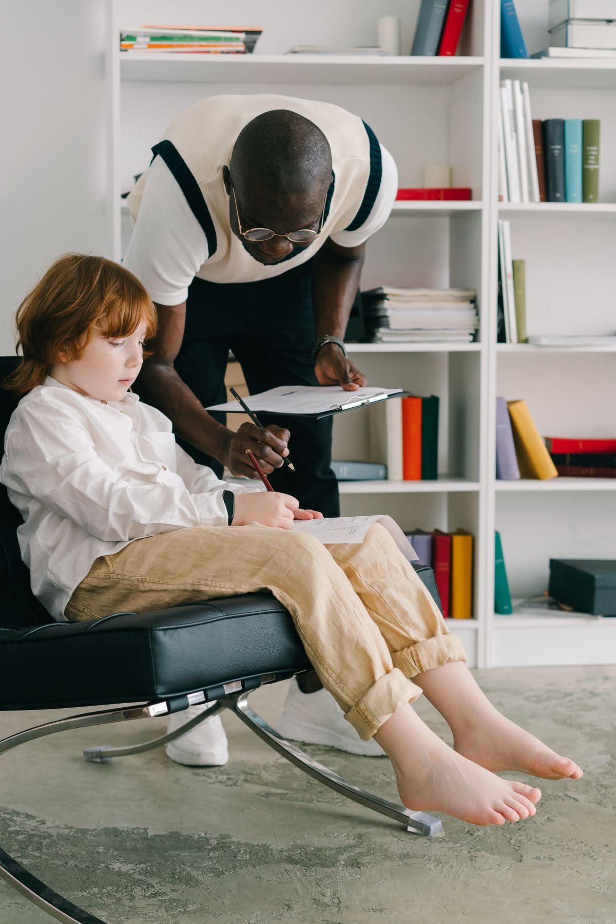 Logopedista che compila una scheda di valutazione insieme a un bambino, seduti a fianco